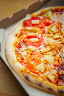 Fast food siparişi. Çiğ hamurlu domatesli ananaslı pizza. İtalyan pizzasından karton paket.