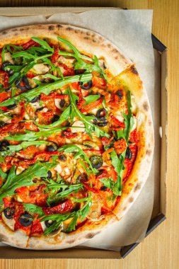 Düz katlı vejetaryen pizzası. Lezzetli İtalyan mutfağı. Rugula, siyah zeytin, kurutulmuş domates ve fırında pişirilmiş beyaz şampiyon mantarı.