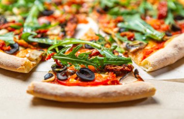 Fast food teslimatı. Siyah zeytinli rugula pizza, karton kutuda kurutulmuş domates ve mantar. Yakından İtalyan yemeği.