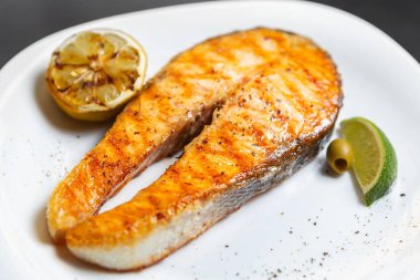 Izgarada pişirilmiş gurme somon balığı. Akşam yemeği için deniz ürünleri restoranında tavada ızgara yapılmış lezzetli kırmızı alabalık bifteği. Keto diyeti için de az yağlı ve yüksek proteinli sağlıklı doğal deniz ürünleri.