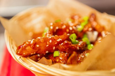 Fast food restoranında öğle yemeği için susam tohumlu kızarmış tavuk şeritleri ve kahverengi kağıtta yeşil soğan.