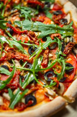 Gazi pizzası yakın mesafede. Rugula, kuru domates, dilimlenmiş taze domates, beyaz şampiyon mantarları, fırında pişirilmiş siyah Yunan zeytinleri geleneksel İtalyan tarifi ile fast foord restoranında.