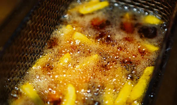 French fries cooking in hot oil.Fast food restaurant cookes potato chips for take away menu.American fastfood diner cook order for delivery