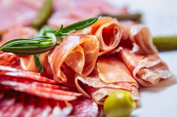 Delicious meat snacks for dinner.Sliced Spanish jamon,pepperoni sausages,beef ham served on plate in restaurant for snack.Gourmet Mediterranean food for wine appetizer