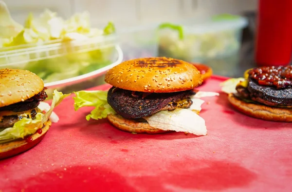 Fast food cooking in restaurant kitchen.Burgers with rare black blood puddling steak in crusty buns.Delicious American fastfood meal for dinner being prepared for take away order.Enjoy natural meat