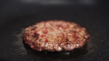 Geleneksel Amerikan hamburgeri yakından pişiriliyor. Mutfakta kızgın tavada kızartılmış domuz eti. Hamburger yemeği için doğal malzeme.