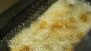 Patates kızartması, Amerikan fast food restoranının mutfağında kızartılıyor. Yukarıdan yakından çekilmiş. Akşam yemeği için kızgın yağda kızartılan sağlıksız yağlı abur cubur. 