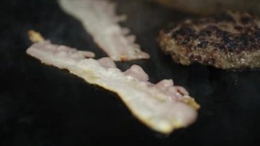 Akşam yemeği için Amerikan fast food restoranında domuz pastırması ve ızgara et pişirme. Yağlı ve sağlıksız abur cubur, yüksek kolesterollü, yakın çekim görüntülerinde kızartılmış yağ. Kötü diyet kavramı.