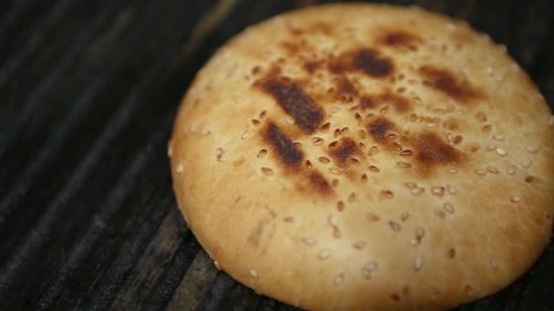 烤面包 用芝麻做的面包 放在烤架上 与脚靠得很近 在快餐店厨房里 用新鲜的粗硬的面包做汉堡包 在火热的表面烤着吃晚餐 — 图库视频影像