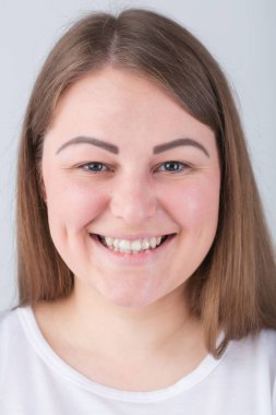 Güzel, iri yarı, dişlek bir gülümsemesi olan genç bir kadın. Beyaz dişli ve neşeli bir ifadeyle kameraya gülümseyen güzel beyaz bir kadın model. Arkadaşça gülümseyen küstah bir kız.