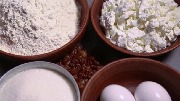 チーズケーキを調理するために用意された天然成分 小麦粉 柔らかいコテージチーズ 白い鶏の卵 乾燥レーズンは レストランキッチンで上記からズームアウト効果で撮影 — ストック動画