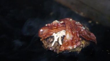 Fast food restoranında et kızartılıyor. Hamburger için domuz pirzolası pişirme videosunu kapatın. Geleneksel Amerikan lokantası yemeği sıcak yüzeyde kızartılıyor.