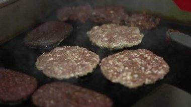 Fast food restoranında et kızartılıyor. Hamburgerler için pişirilen domuz pirzolası videolarını kapatın. Geleneksel Amerikan lokantasında akşam yemeği için tavada kızartma köftesi.