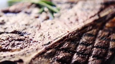 Et lokantasında beyaz tabakta ızgara biftek servis edilir, yukarıdan zoom efektiyle filme alınır. Biberli ızgara sığır eti videosu yakın, akşam yemeği için biberiye baharatı.