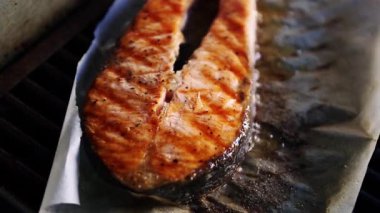 Deniz ürünleri restoranında ızgarada pişirilen lezzetli somon balığı bifteği. Sıcak ızgara yüzeyinde pişirilen lezzetli doğal kırmızı balık filetosu video klipsiyle. Sağlıklı doğal deniz ürünleri. 
