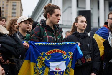 Genç Ukraynalı adam, 2022 'den beri Rus kuvvetleri tarafından işgal edilen Mariupol şehrinin bayrağını taşıyor. Kyiv - 24 Şubat 2024