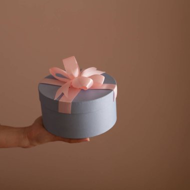 Güzel bir kadının elinde pembe bir yay ile mavi hediye kutusu yuvarlak