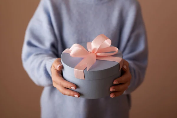 美丽的圆形蓝色礼品盒 在一个女人的手中有一个粉红色的蝴蝶结 — 图库照片