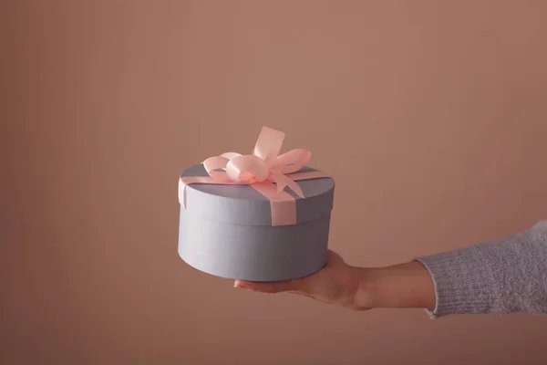 美丽的圆形蓝色礼品盒 在一个女人的手中有一个粉红色的蝴蝶结 — 图库照片