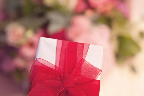 Confezione Regalo Primo Piano Con Fiocco Rosso Sfondo Fiori — Foto Stock