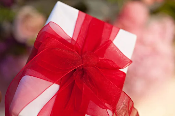 Nahaufnahme Geschenkbox Mit Roter Schleife Auf Blumen Hintergrund — Stockfoto