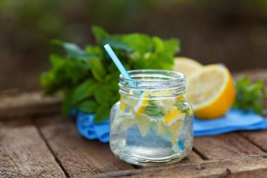 Ahşap arka plan üzerinde bir cam kupa taze doğal limon içecek