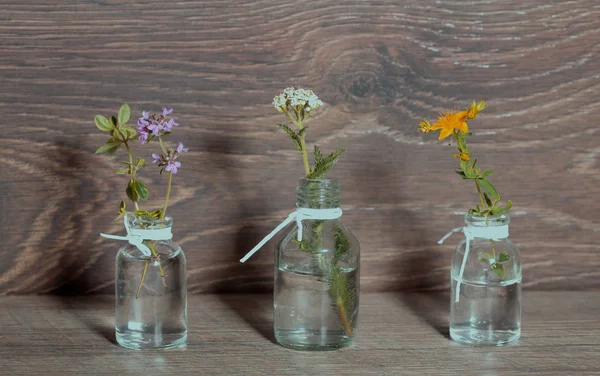 A bottle of essential oil with herbs, parsley, thyme, dill, hyssop, set on an old wooden background. Cooking, alternative medicine, massage, aromatherapy concept. — Stock Photo, Image