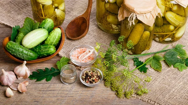 Bodegón con pepinos frescos y en escabeche en frascos, especias en mesa de madera. Legumbres conservadas —  Fotos de Stock