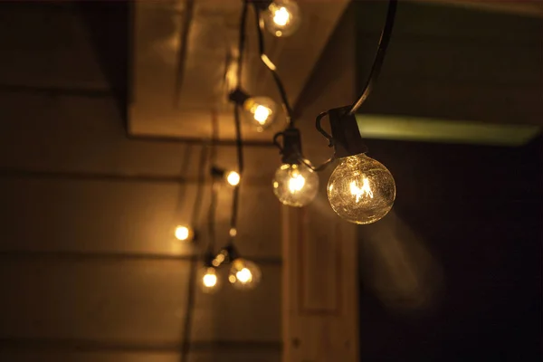 Luzes decorativas de corda ao ar livre penduradas na árvore no jardim à noite — Fotografia de Stock