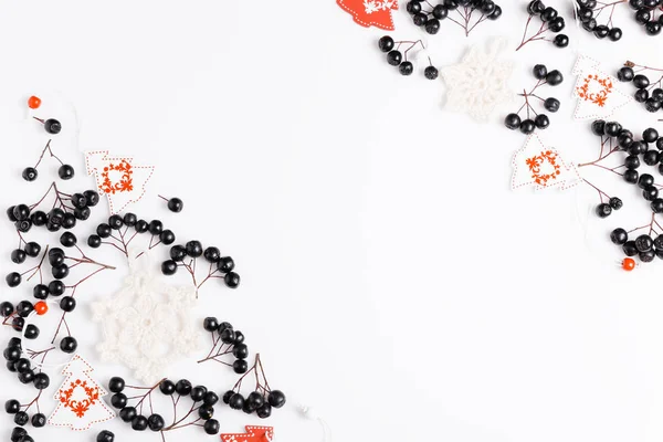 Composizione natalizia. Bacche di chokeberry nero, palle di neve bianche lavorate a maglia e alberi di Natale bianco-rossi su sfondo bianco. Layout piatto, vista dall'alto, spazio di copia — Foto Stock