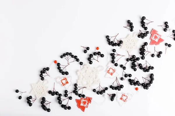 Composizione natalizia. Bacche di chokeberry nero, palle di neve bianche lavorate a maglia e alberi di Natale bianco-rossi su sfondo bianco. Layout piatto, vista dall'alto, spazio di copia — Foto Stock