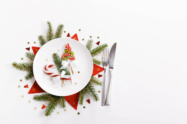 Elegante weihnachtliche Tischdekoration von oben eingefangen, flach gelegt. leerer weißer Teller, Glas, Besteck, Zuckerrohr und Dekorationen. — Stockfoto
