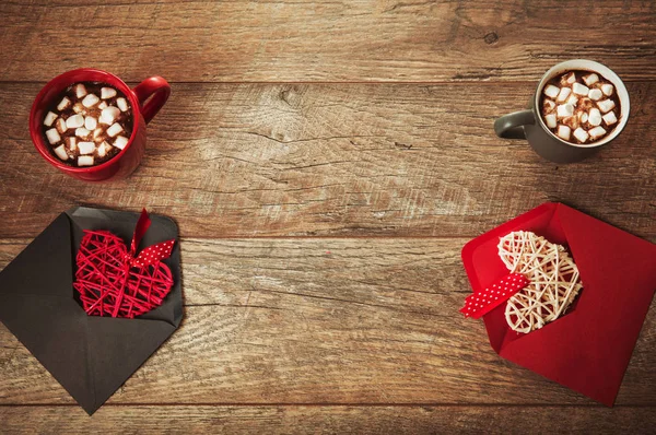 Festive composition on rustic wood table, red and gray mug with marshmallows or cocoa, hearts in envelopes, dried rose flowers. Copy space. Birthday, Valentines, Womens, Wedding Day concept — Stock Photo, Image