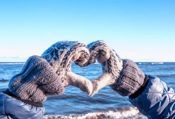 Winter gloves heart symbol shaped lifestyle in the snow against the background of Baltic sea.