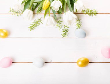 Paskalya yumurtaları ve bahar çiçekleriyle paskalya arkaplanı. Kopyalama alanı olan üst görünüm