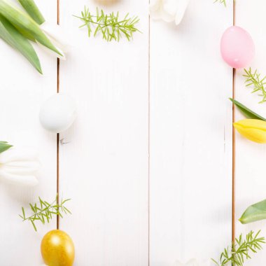Paskalya yumurtaları ve bahar çiçekleriyle paskalya arkaplanı. Kopyalama alanı olan üst görünüm