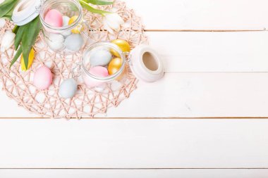 Paskalya arka plan cam Beyaz ahşap masa üzerinde pembe, mavi, altın yumurta ile