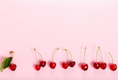 Tropikal yaz soyut arka plan. Pembe arka planda kesimler ve yapraklar ile Kiraz kiraz.