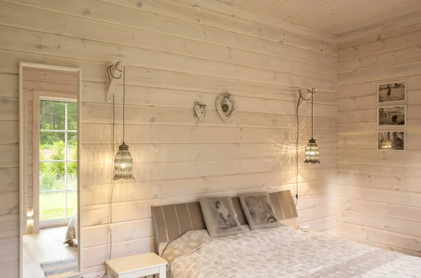 Інтер'єр білого спальні в будинку з білою дерев'яною обробкою з меблями, ліжком, лампами, дзеркалом. Скандинавський стиль — стокове фото
