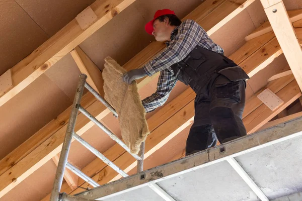 Construction worker thermally insulating eco wooden frame house — Stock Photo, Image