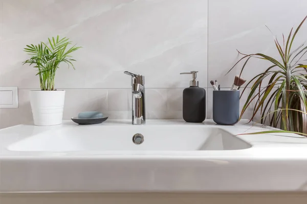 Interiér koupelny s umyvadlem, umyvadlem, mýdlem a zelenými tropickými rostlinami. Moderní design koupelny — Stock fotografie