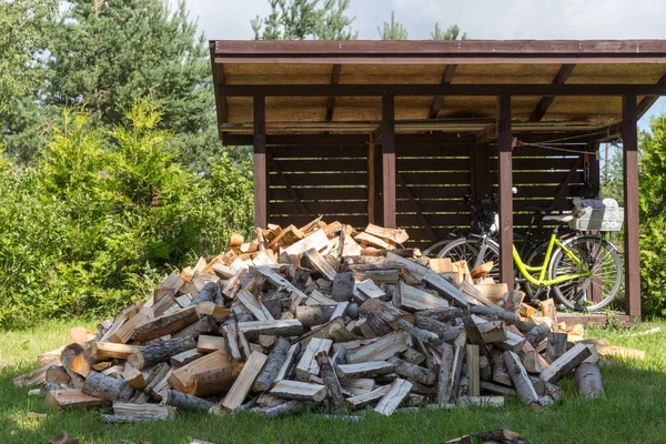 Im Winter geerntetes Brennholz zum Heizen. Ein Haufen Brennholz im Hof des Hauses auf dem grünen Gras — Stockfoto