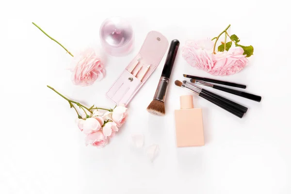 Pinsel, Kosmetik und rosa Rose auf weißem Hintergrund — Stockfoto