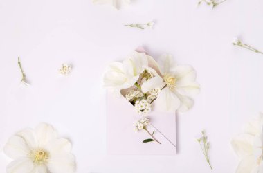 Beyaz romantik tatil çiçekleri, klematis, çiçeklerle dolu pembe zarf, düğün, aşk konsepti