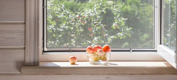 Ventana blanca con mosquitero en una casa de madera rústica con vistas al jardín. Manzanas ecológicas en tazón en alféizar de ventana. — Foto de Stock