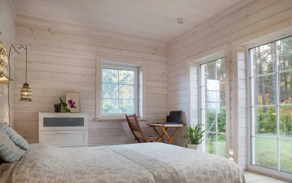 Dormitorio blanco con elementos de decoración simples en una elegante casa de madera. Lugar de trabajo en el dormitorio, una mesa y un ordenador — Foto de Stock