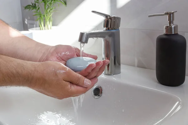 Der Mensch benutzt Seife und wäscht sich die Hände unter dem Wasserhahn. Hände mit Seife waschen — Stockfoto