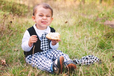 Sevimli küçük çocuk yeşil çim - oturan topuz komik çocuk yiyor.