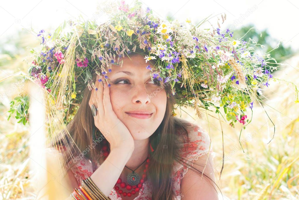 Beautiful happy woman in flower wreath in summer