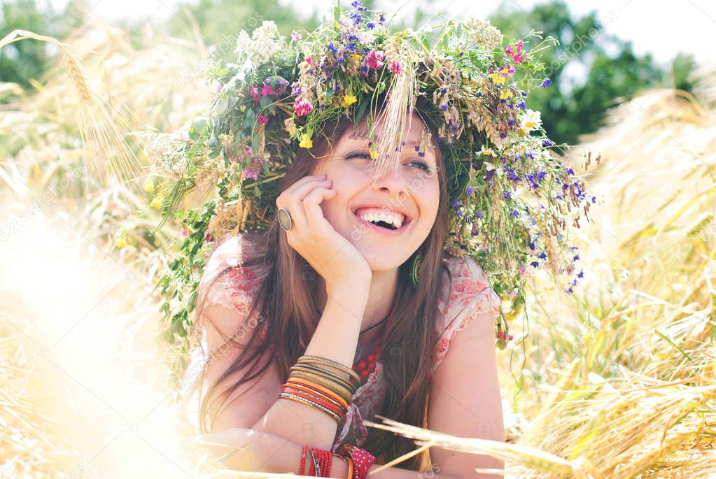 Beautiful happy woman in flower wreath in summer